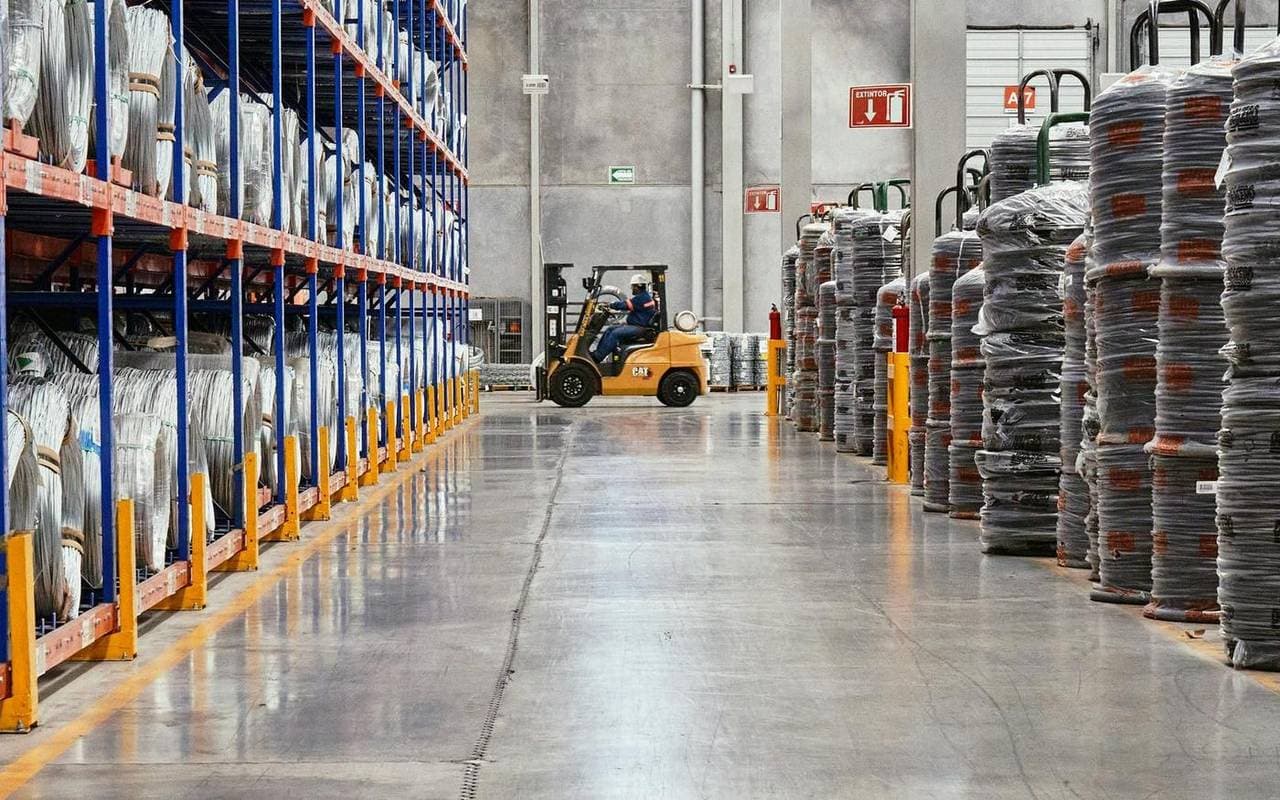 Montacargas moviendo inventario en el pasillo de una bodega de distribución