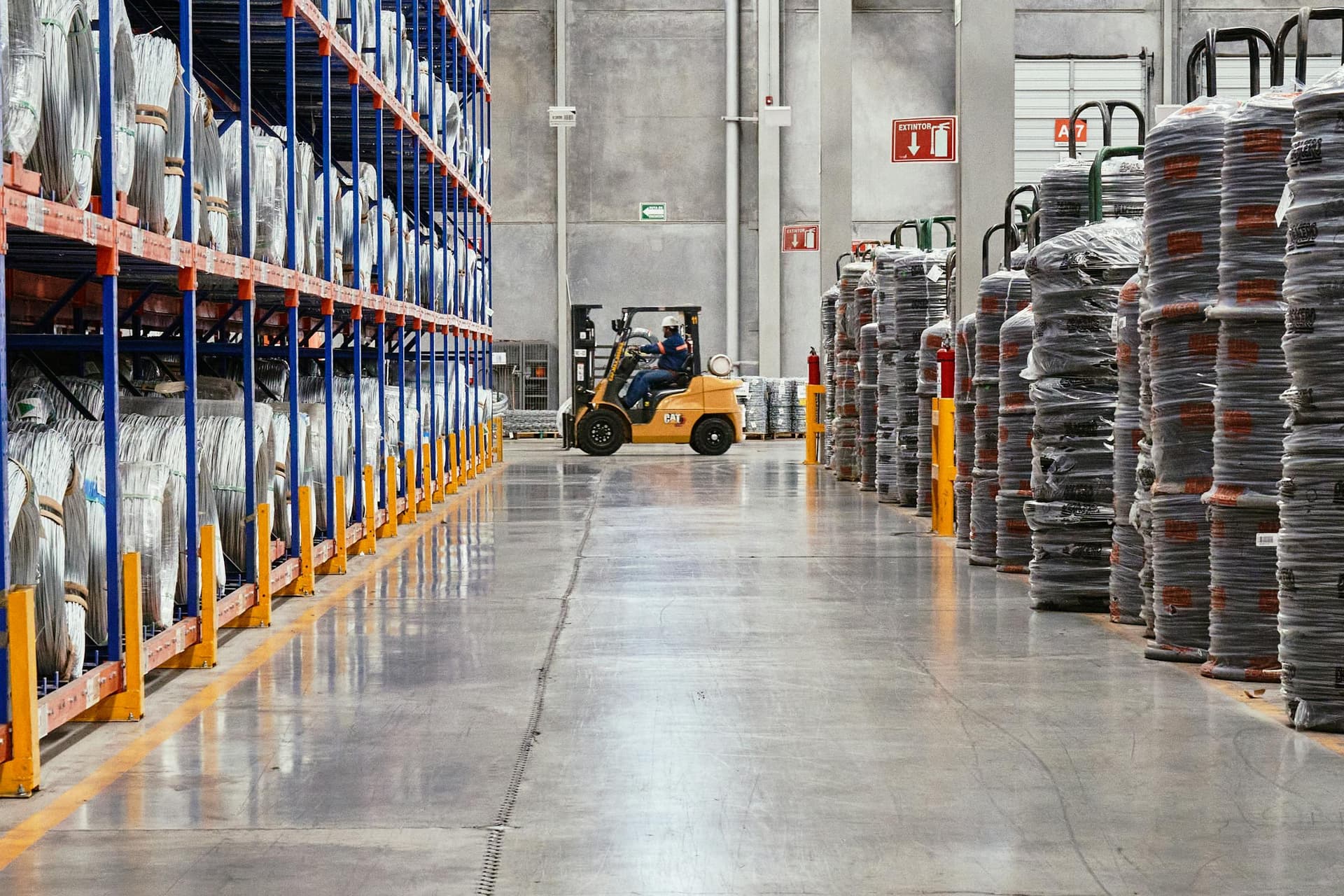 Forklift operating in an industrial warehouse with stacked goods — Voltera wholesale distribution model