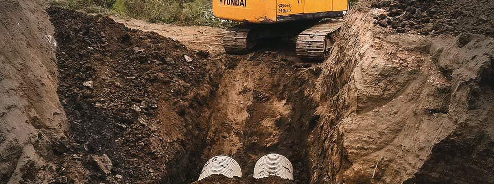 Large-diameter corrugated sewer pipe being laid in an open trench