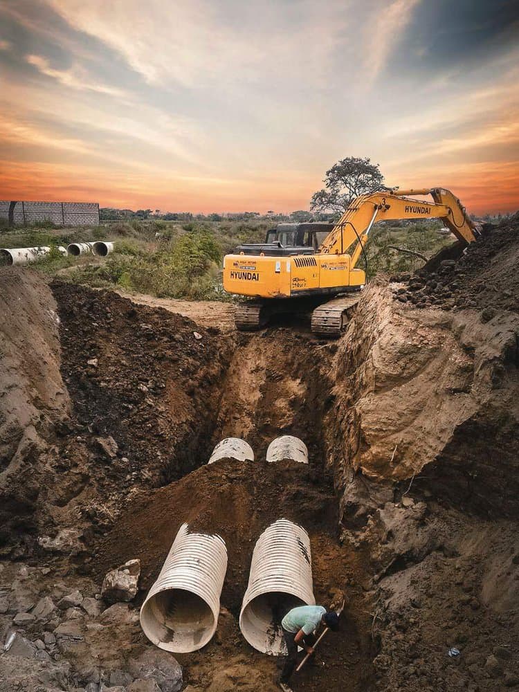 Large-diameter corrugated pipe being laid in an open trench